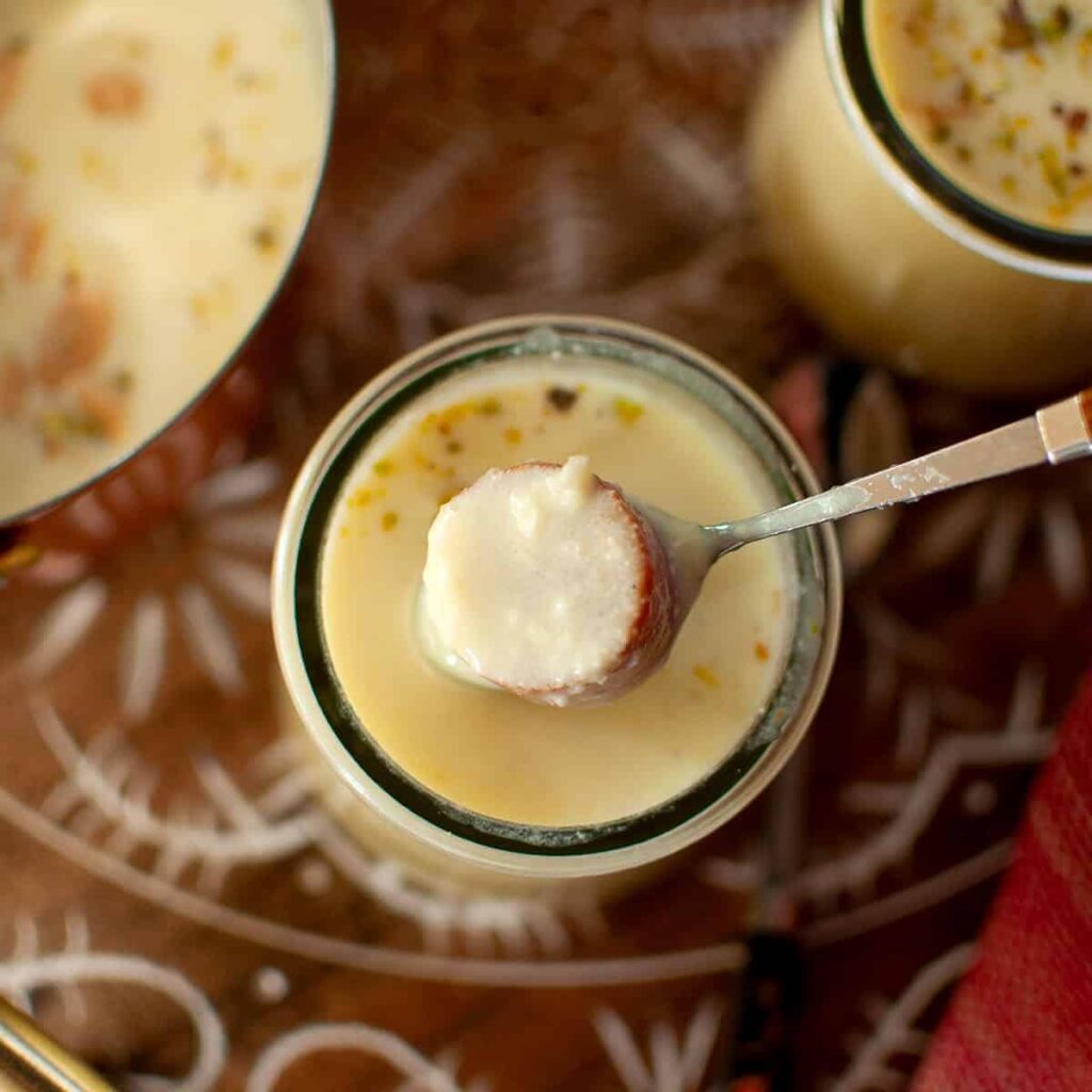 Spoon with jamun with a jar of rabri.