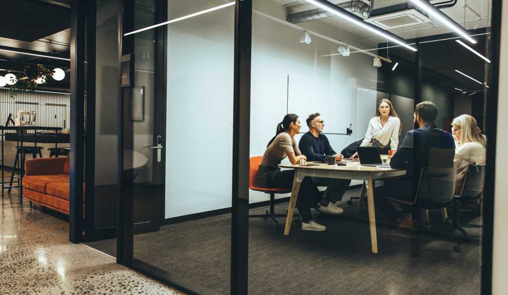 Team of diverse businesspeople having a meeting in a transparent boardroom. Group of business professionals having a discussion during a briefing. Colleagues collaborating on a new project.