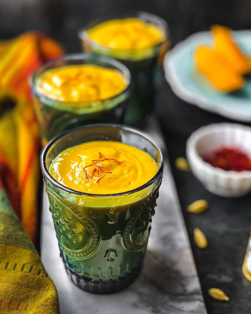 Three glasses of Mango Lassi served on a marble slab