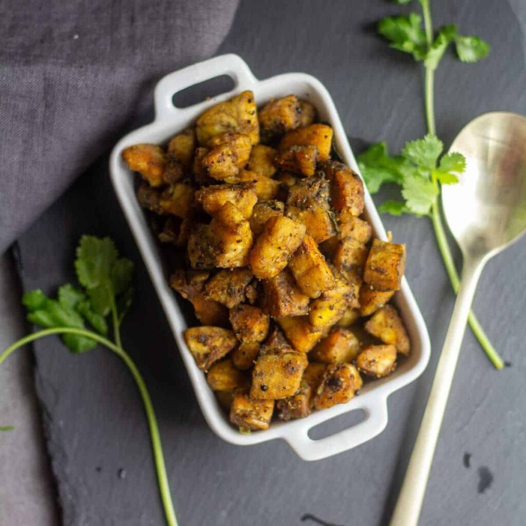 square image of plantain roast placed on slate board with cilantro on the side