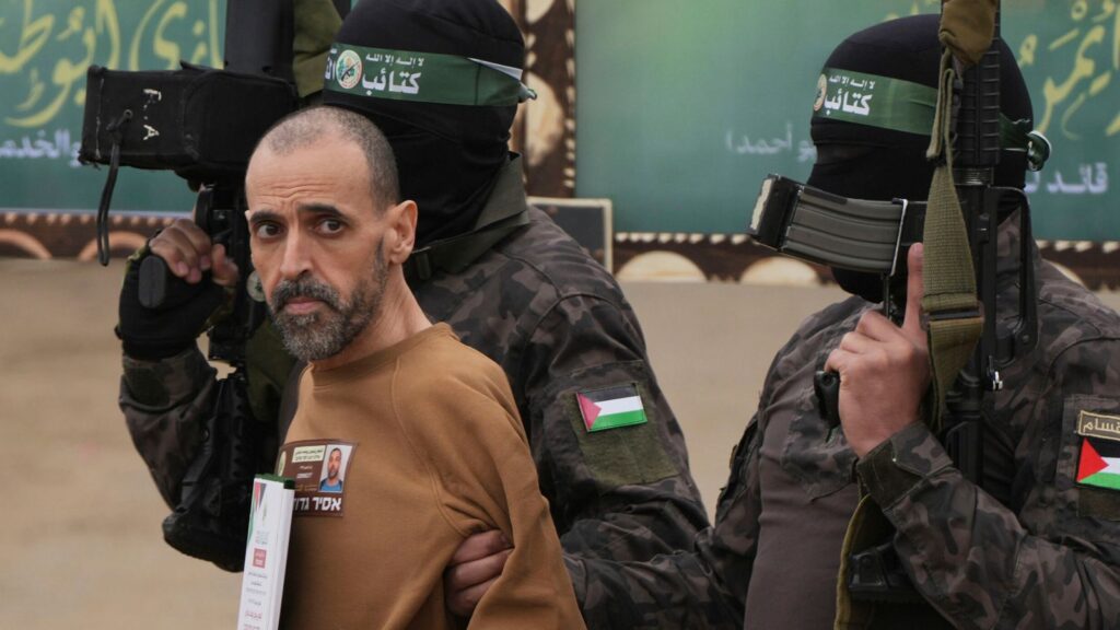 Israeli captive Eli Sharabi, is escorted by Hamas fighters before being handed over to the Red Cross. Pic: AP