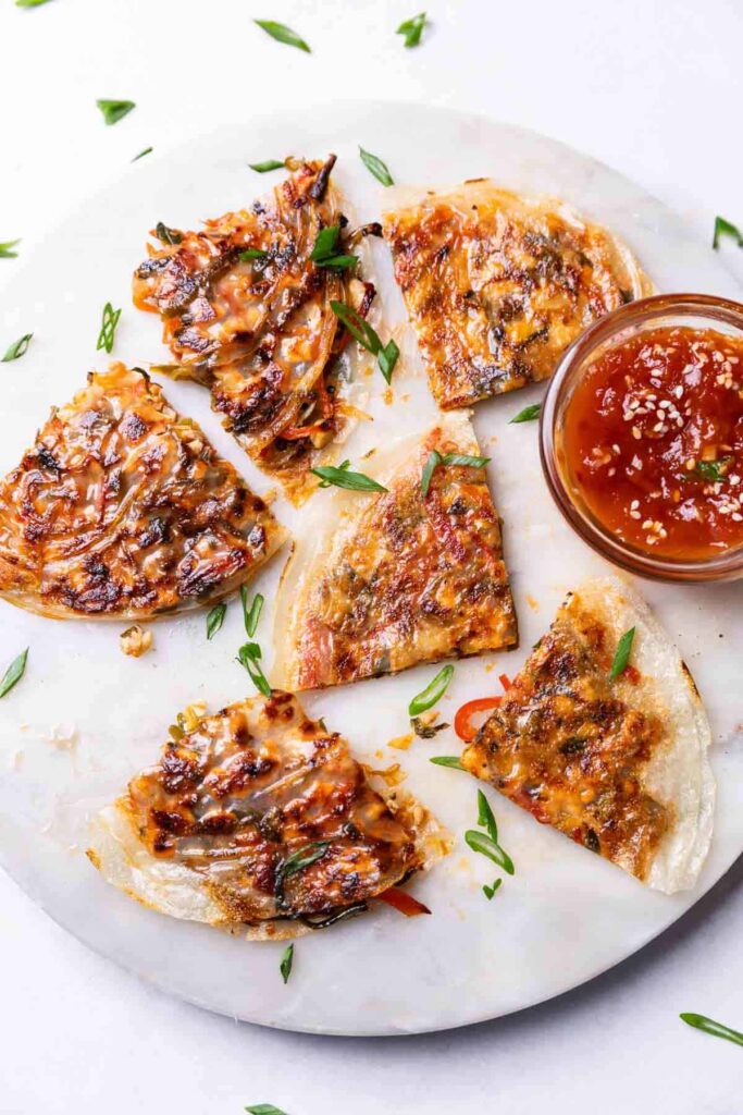 rice paper pancakes served on a round white platter with a dipping sauce