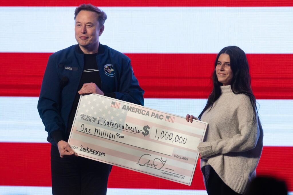 Elon Musk gives $1,000,000 to a Wisconsin voter, Ekaterina Diestler, during a town hall meeting he was hosting at the KI Convention Center on March 30, 2025 in Green Bay, Wisconsin.