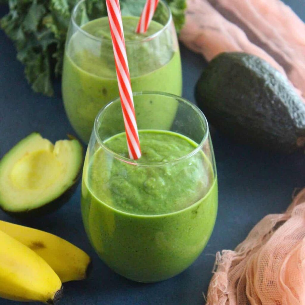 kale smoothie in a glass to help in weight loss along with avocado and kale around