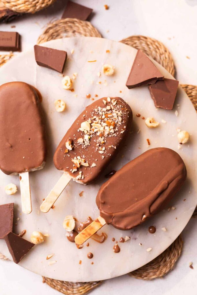 healthy chocobar ice creams garnished with chopped nuts and placed on a white platter