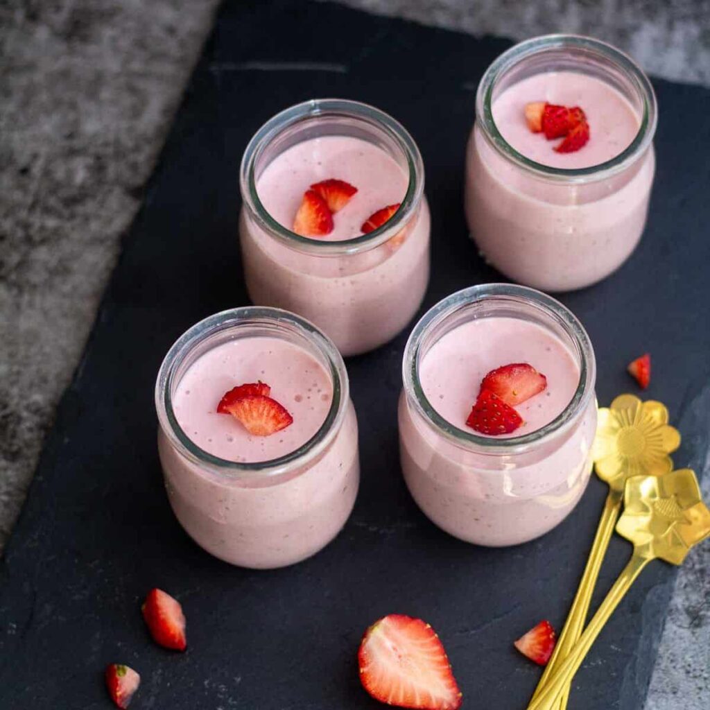 square image of 4 strawberry panna cotta served in jars
