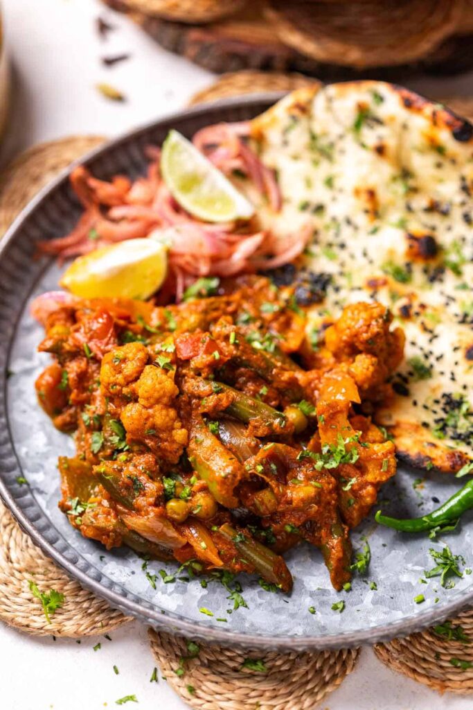 veg kadai served on a platter with naan and onion salad
