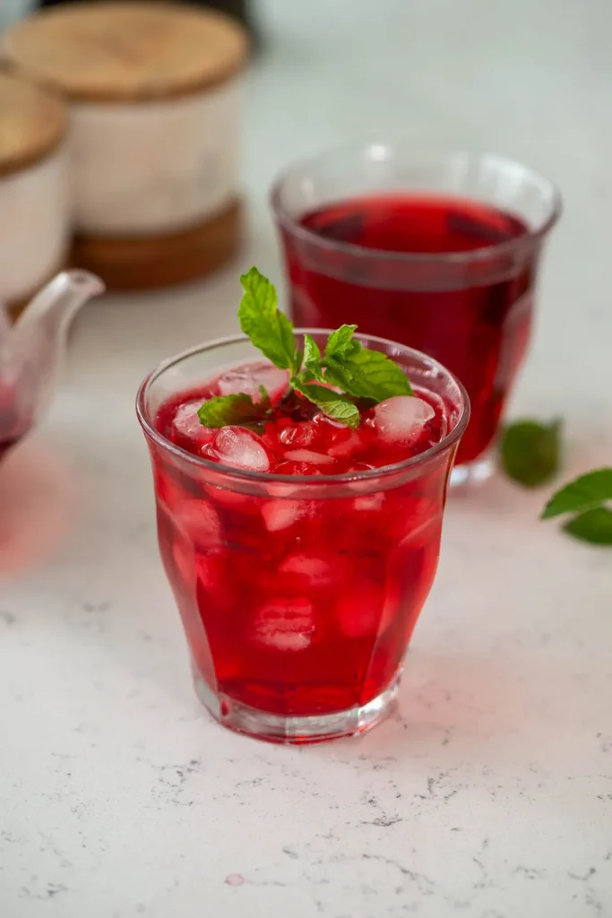 Hibiscus tea recipe – ruby-red iced hibiscus tea in a clear glass with lime wedge and ice cubes